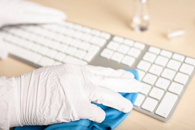 消毒剤でキーボードを洗浄する手袋をした手 Covid 19コロナウイルスの発生汚染防止の概念 プレミアム写真
