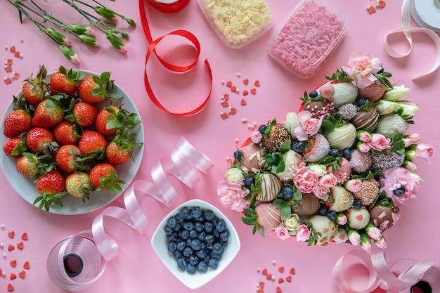 手作りのチョコレートカバーイチゴ 花 ピンクの背景にデザートを調理するための装飾 プレミアム写真