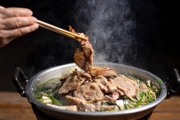 Premium Photo | Hands are using chopsticks to thai barbecue buffet with  smoke.