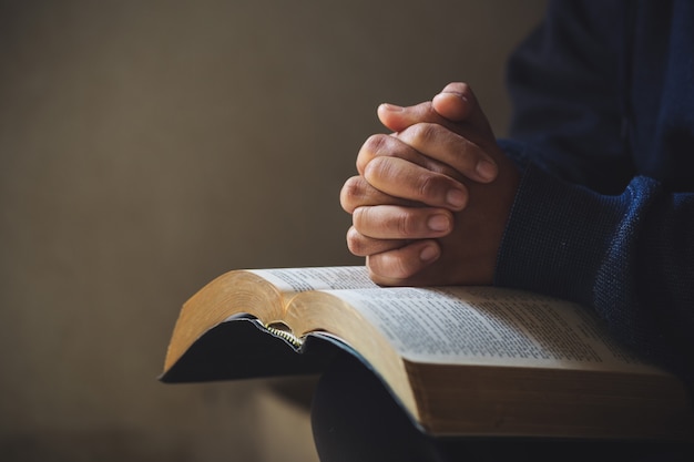 Premium Photo Hands Folded In Prayer On A Holy Bible In Church