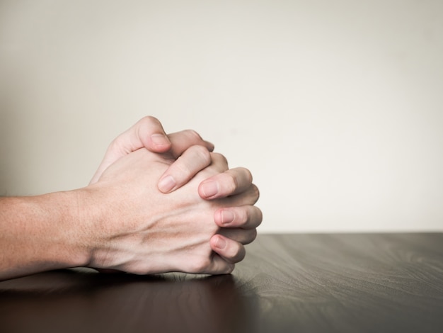 Premium Photo | Hands folded together on the table, praying concept