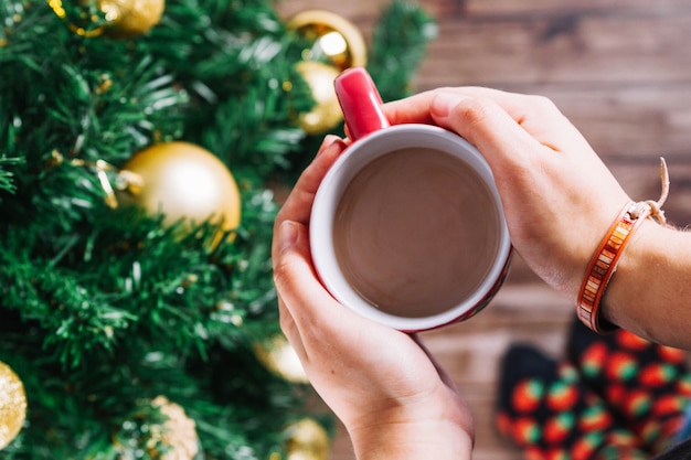 Free Photo | Hands holding coffee mug at christmas tree