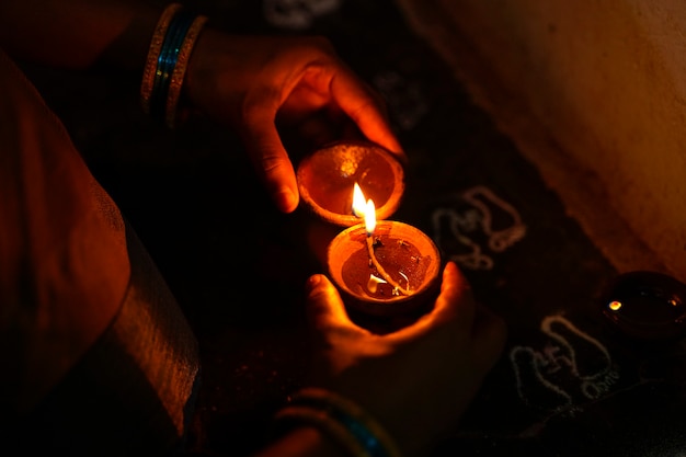 Premium Photo | Hands holding diwali lamps