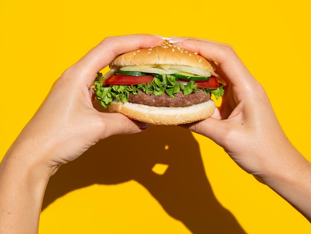 Free Photo | Hands holding perfect burger on yellow background