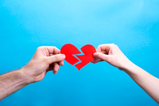 Premium Photo Hands Of Man And Woman Tearing A Red Paper Heart On Blue