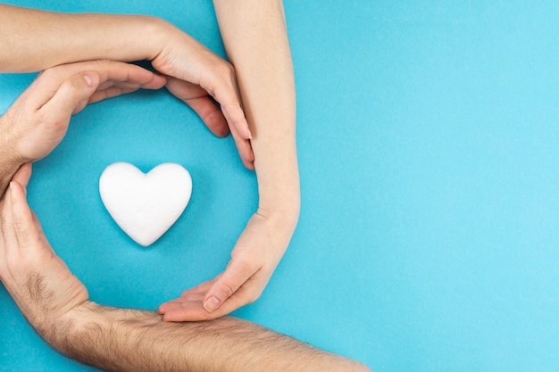 Premium Photo | Hands of parents and a child surround a white heart on ...