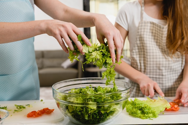 Premium Photo | Hands pour greens for salad in bowl