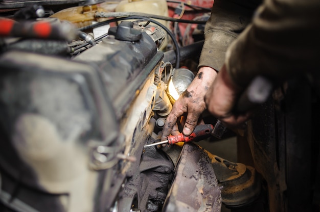 Hands of repairman mechanic working on engine using tool Premium Photo