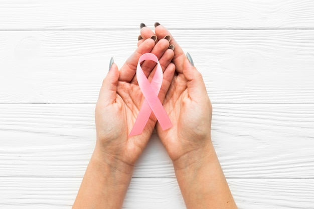 Hands with pink ribbon over timber background Free Photo