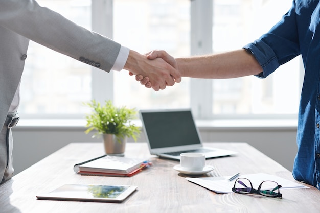 Premium Photo | Handshake of two young business partners over desk with ...