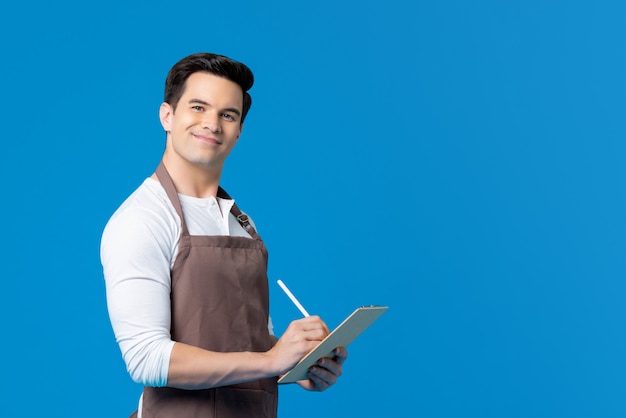 Handsome barista wearing apron writing order on clipboard Premium Photo