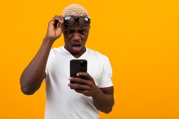 眼鏡のハンサムな黒人アフリカ人がコピースペースと黄色の電話で驚きに見える プレミアム写真