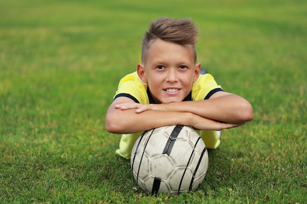 Premium Photo | Handsome boy soccer player lies on the soccer field ...