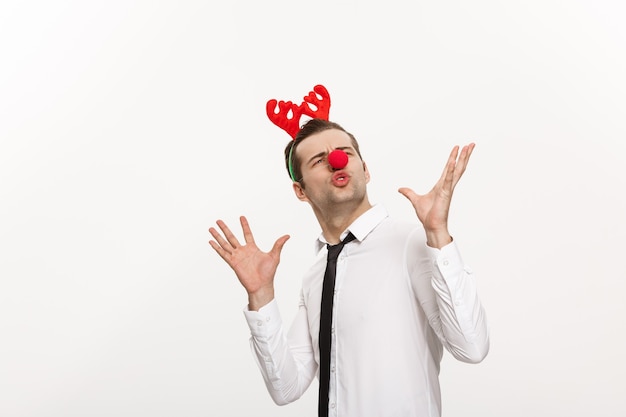 Handsome business man wearinging reindeer hairband making funny facial expression isolated on white. Free Photo