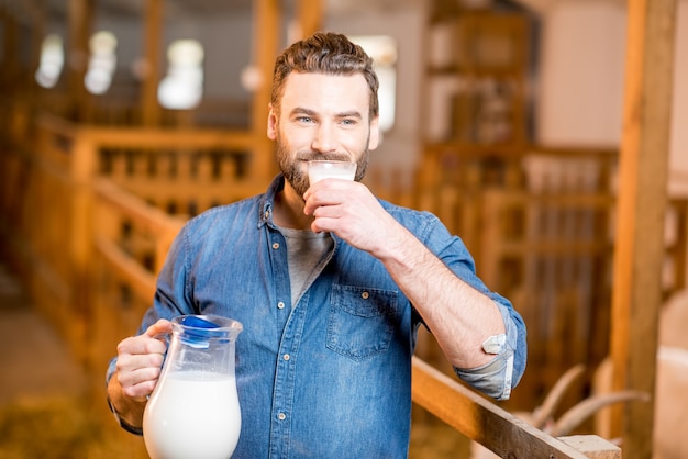 Premium Photo | Handsome farmer tasting fresh milk standing in the goat ...