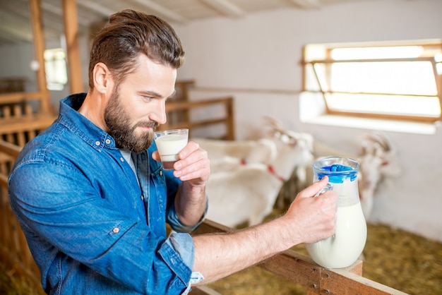 Premium Photo | Handsome farmer tasting fresh milk standing in the goat ...