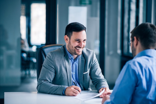 Handsome male client signing document on a meeting with real estate agent. Premium Photo