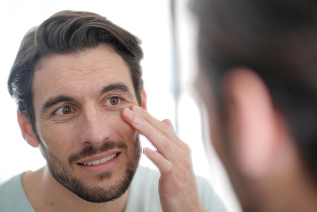 Premium Photo | Handsome man checking wrinkles in mirror at home