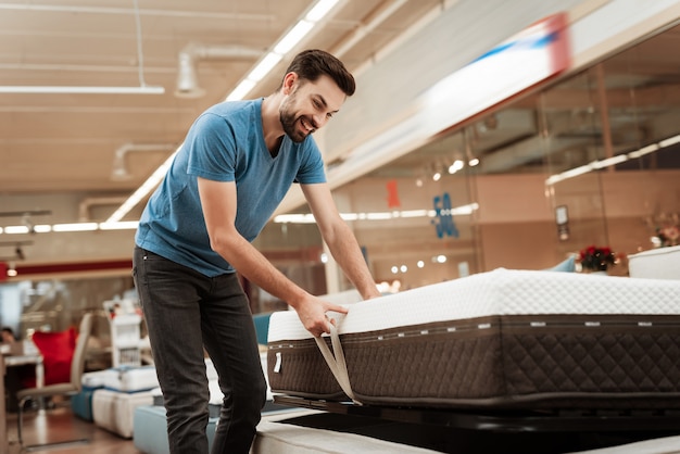 Premium Photo | Handsome man choosing mattress in furniture store