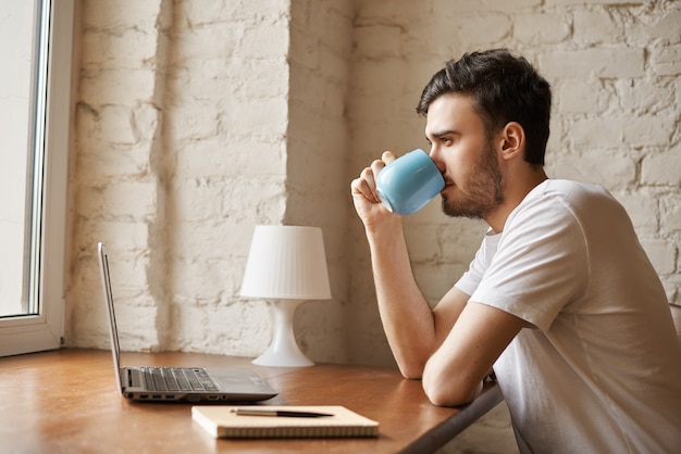 Handsome man drinking coffee after freelance work Free Photo