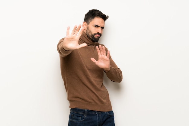 Handsome man over white wall is a little bit nervous and scared stretching hands to the front Premium Photo