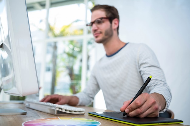 Handsome man working on computer and taking notes in a bright office Premium Photo