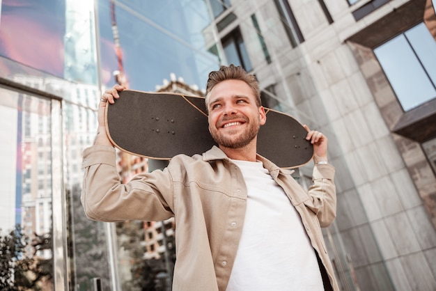 Premium Photo | Handsome young blonde smiling man holding skateboard on ...