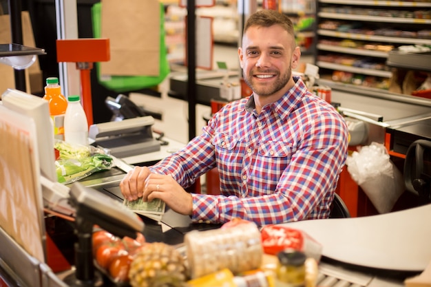 Handsome young cashier working in supermarket Premium Photo