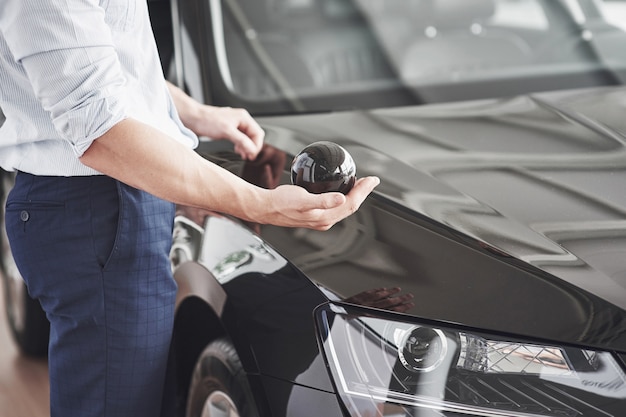 Handsome young man consultant at car salon standing near car. Free Photo