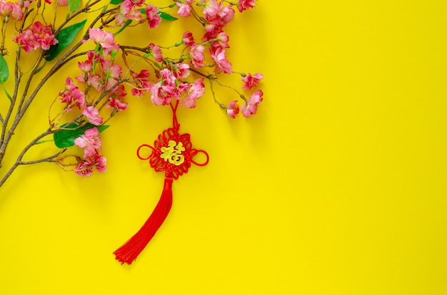 黄色の背景に中国の花の花が付いている中国の旧正月飾り 言葉の意味は富です の吊り下げ式ペンダント プレミアム写真