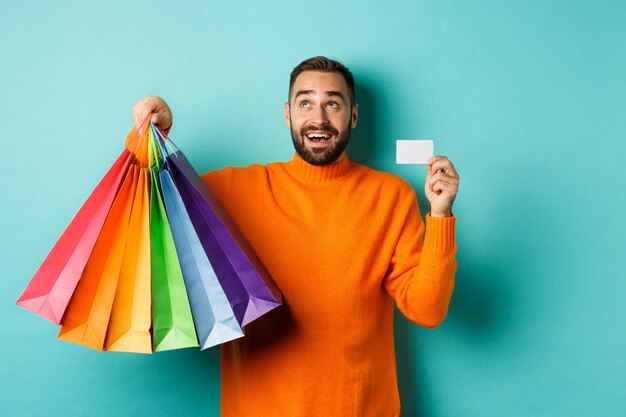 Premium Photo | Happy aduly man showing credit card and shopping bags ...