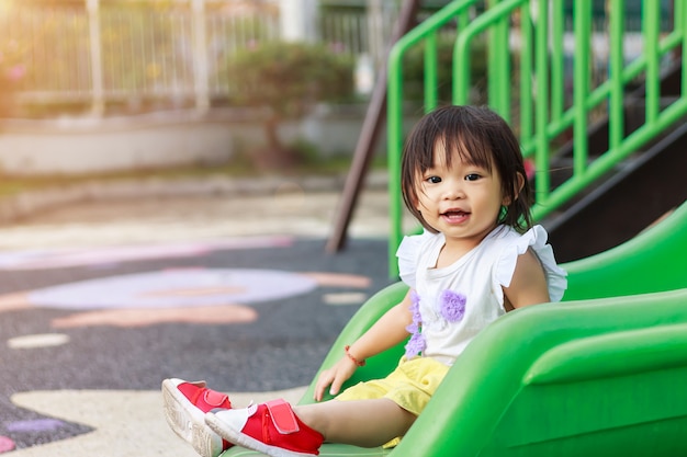 幸せなアジアの子供女の子笑顔と笑い 彼女は遊び場でスライダーバーのおもちゃで遊んでいます プレミアム写真