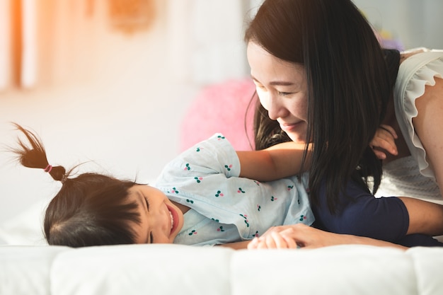 Happy asian family mother with daughter playing on bed with smile face. Premium Photo