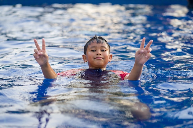 Premium Photo | Happy asian kid boy swiming on swiming pool in the summer