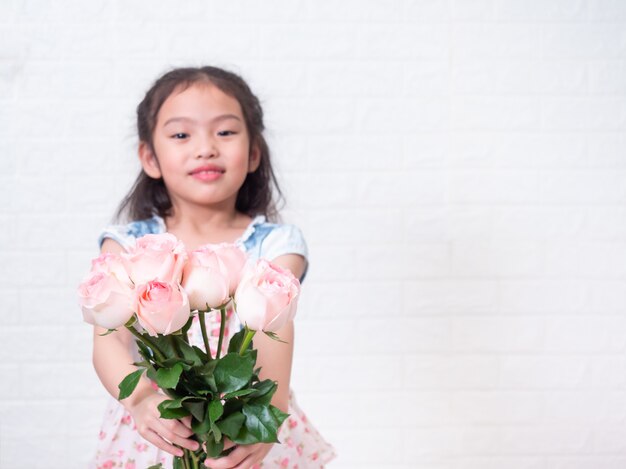 Premium Photo Happy Asian Little Cute Girl Standing And Holding Rose Bouquet Flowers Over White Bricks Wall Selective Focus At Rose