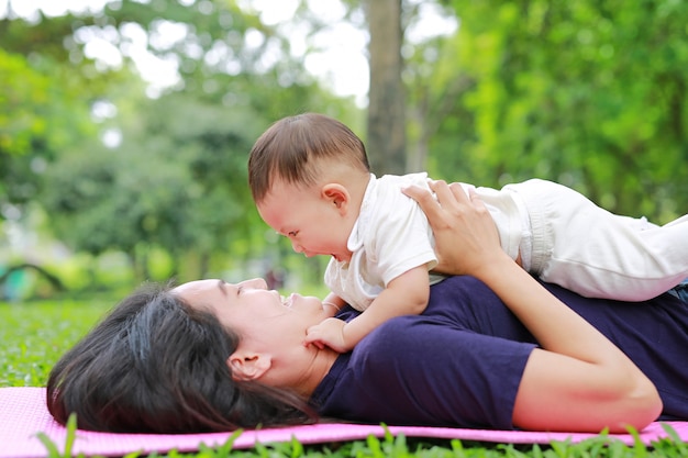 Happy Asian Mom Embrace Her Son Lying In The Green Garden Premiu