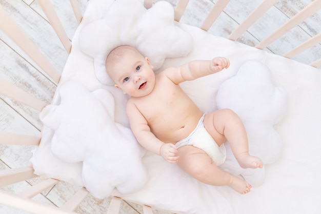 保育園のベビーベッドで幸せな男の子 かわいい面白い 笑っている小さな赤ちゃん6か月の笑顔 健康的な睡眠の概念 プレミアム写真