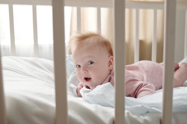 Premium Photo | Happy baby girl looking at camera while creeping in crib