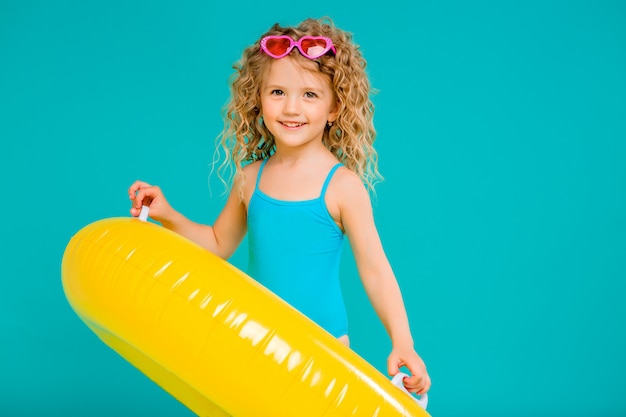 Happy Baby Girl In Swimsuit With Circle Isolated On Blue