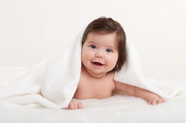 Happy baby under towel on white background Premium Photo