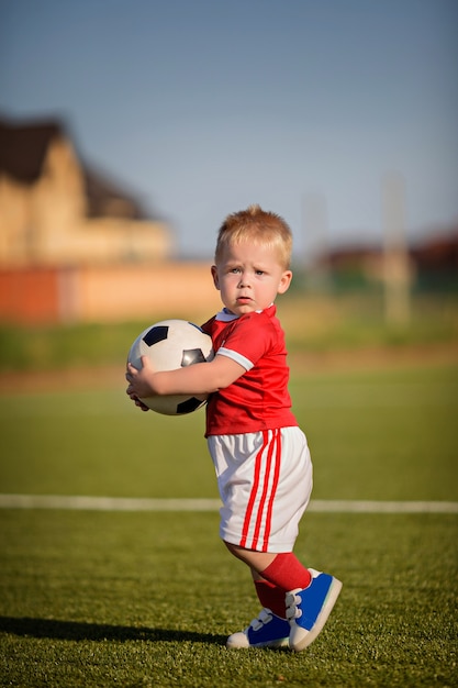 ゲート近くのフィールドでボールとサッカーをして幸せな赤ちゃん男の子 プレミアム写真