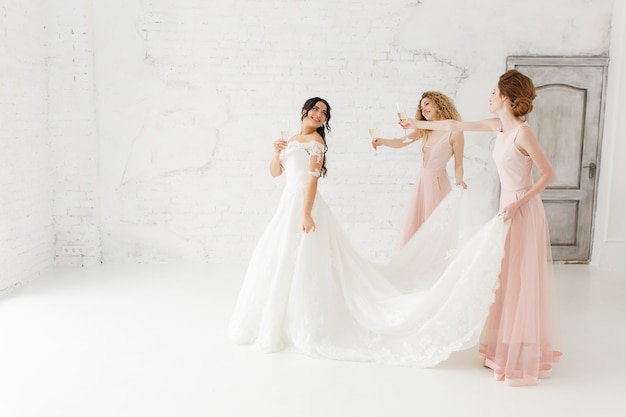 Happy Beautiful Bride And Bridesmaid Adjusting Her Wedding Dress