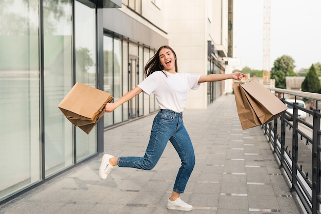 Happy beautiful woman with colorful shopping bags in hand cheerfully jumping in the air. Free Photo