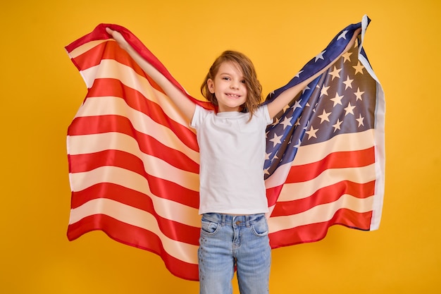 黄色いアメリカのアメリカ国旗を持つ幸せな子かわいい女の子が独立記念日を祝う プレミアム写真
