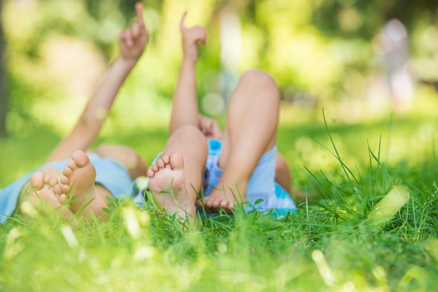 Premium Photo | Happy children lying on green grass and pointing to the sky