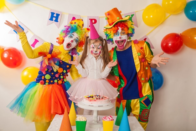 Premium Photo | Happy clowns blow out the candles on the birthday cake ...
