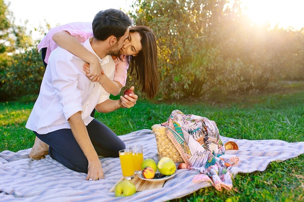 晴れた日に公園でピクニックを持っていること キスしてハグ幸せなカップル 無料の写真