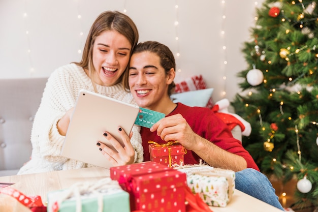 Happy couple looking at tablet with credit card Free Photo