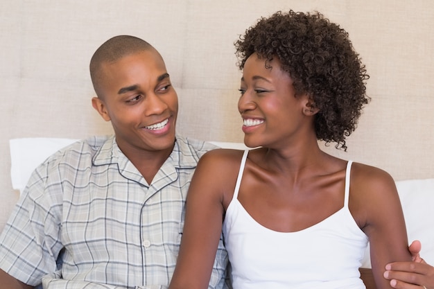 Premium Photo Happy Couple Sitting On Bed Smiling At Each Other