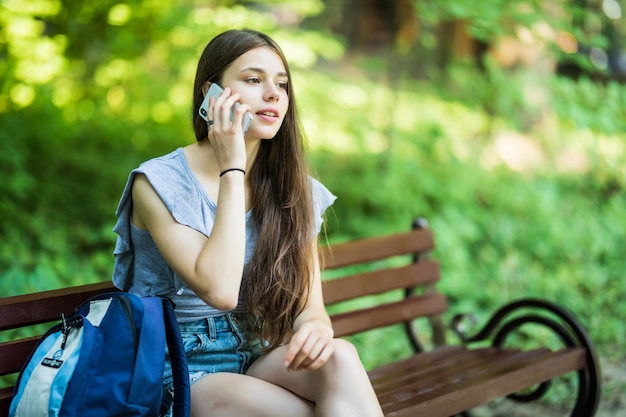 幸せなかわいい白人の若い女性が笑顔で公園で電話で話している 無料の写真